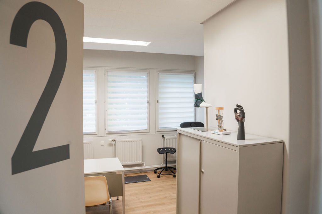 Entrée du cabinet de bandagisterie et orthopédie de la Polyclinique de Fléron, avec présentoirs d'orthèses